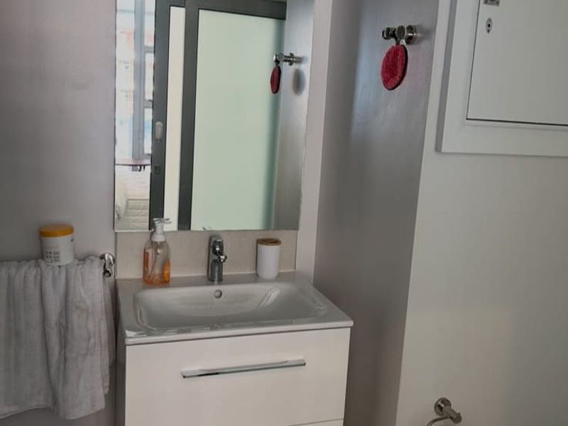 A modern bathroom featuring a wall-mounted vanity with an integrated basin, chrome fixtures, and a large wall mirror.