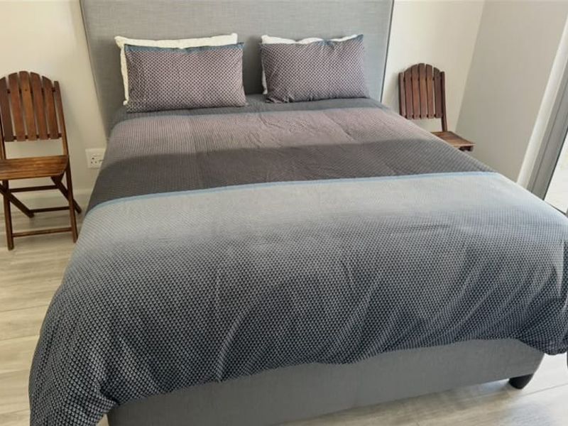 A well-maintained bedroom featuring a large upholstered headboard and light-toned laminate flooring.