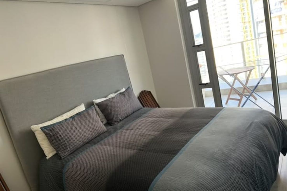 A modern bedroom featuring a large sliding glass door that provides access to a private balcony and allows for ample natural light.