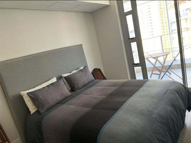 A modern bedroom featuring a large sliding glass door that provides access to a private balcony and allows for ample natural light.