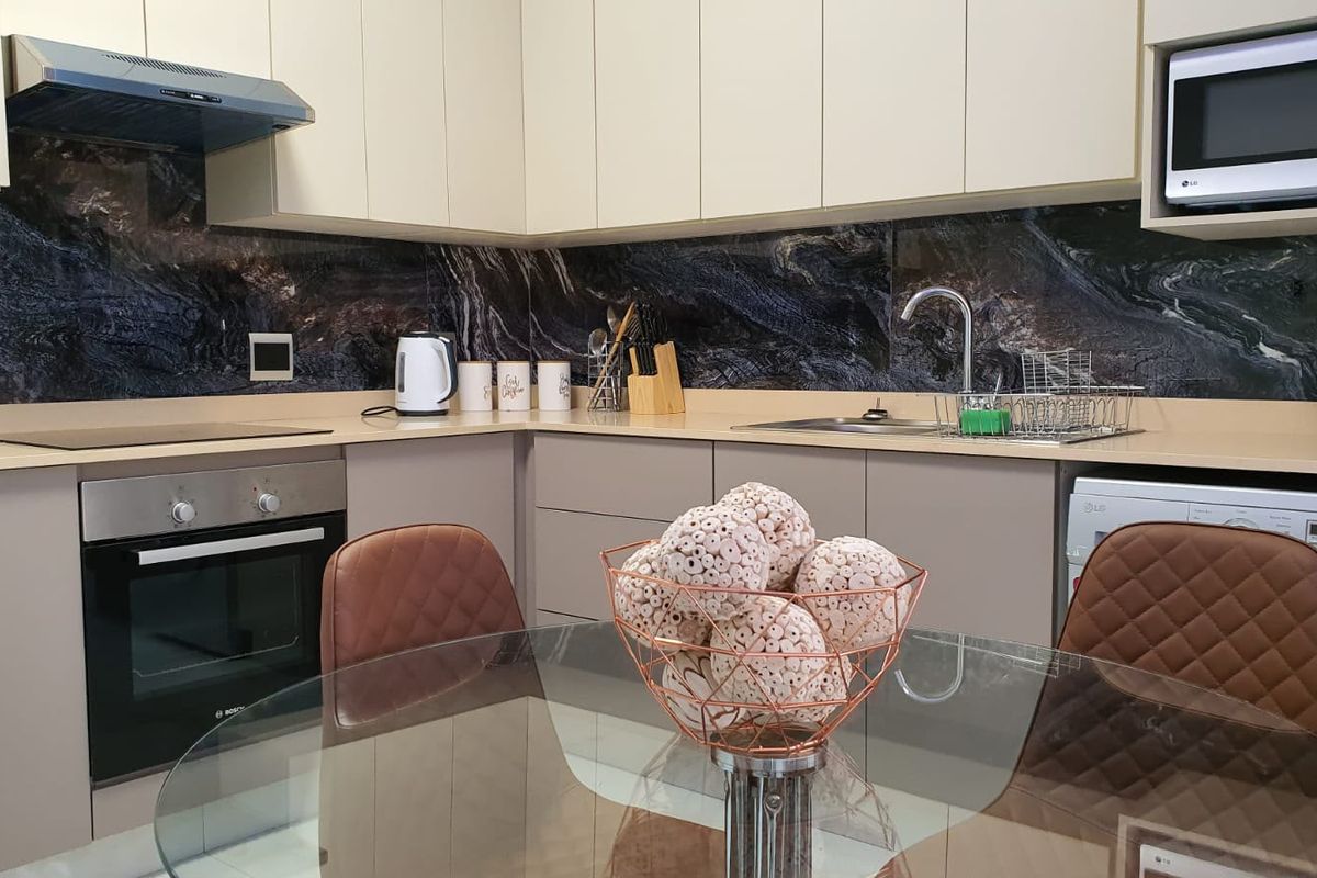 Modern kitchen featuring sleek cabinetry, stone countertops, a striking marble-effect splashback, and integrated appliances including an oven, microwave, and extractor fan.