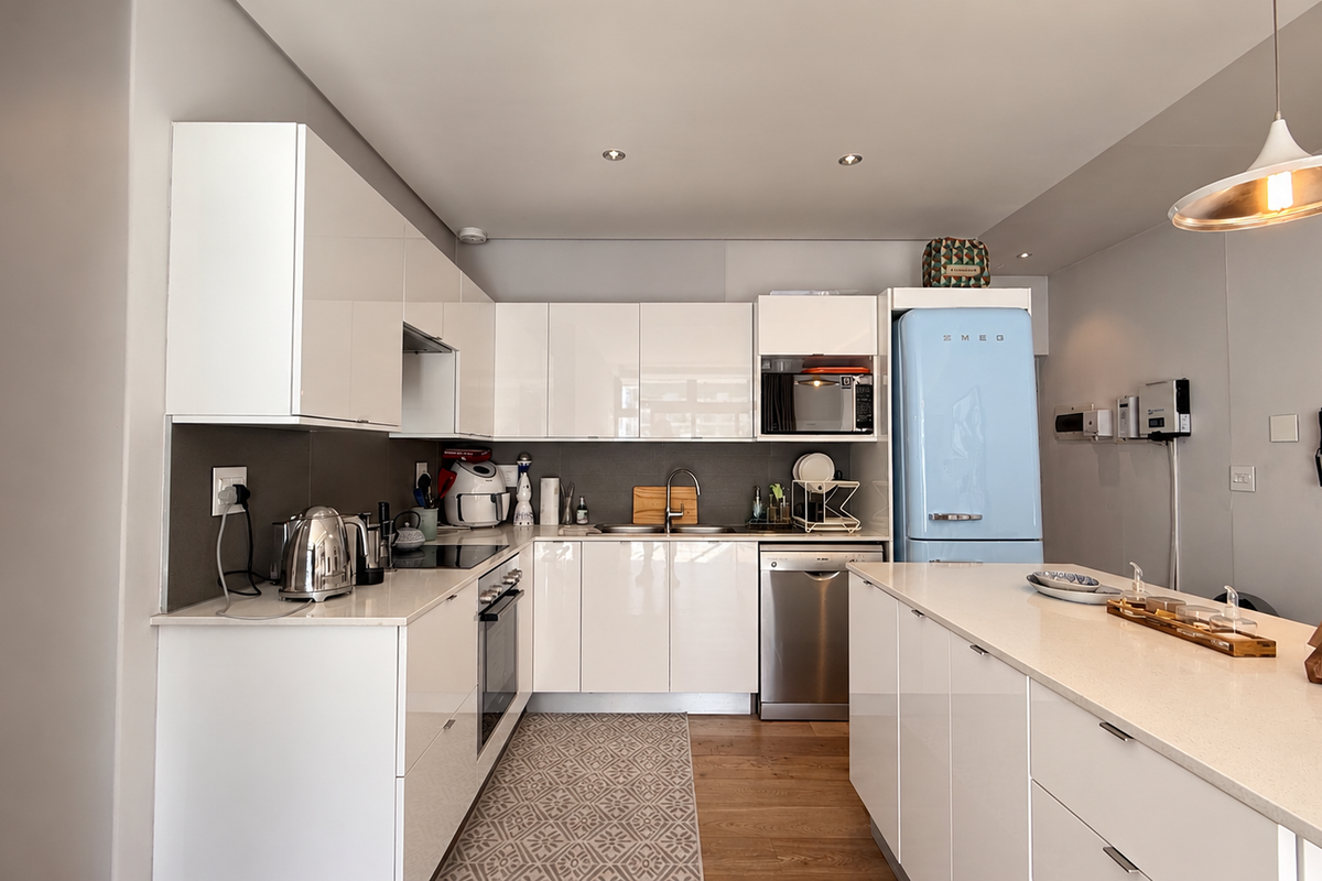 Modern kitchen featuring high-gloss white cabinetry, stone countertops, integrated appliances, and a functional island layout with contemporary lighting.