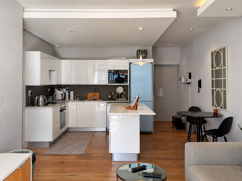 Modern open-plan kitchen featuring sleek white cabinetry, a central island, and high-quality hardwood flooring, seamlessly integrated with the living and dining area.