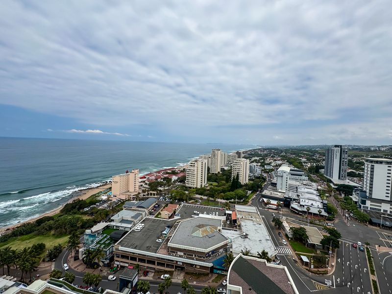 Elevated coastal view overlooking the ocean, surrounding urban infrastructure, and local commercial buildings.