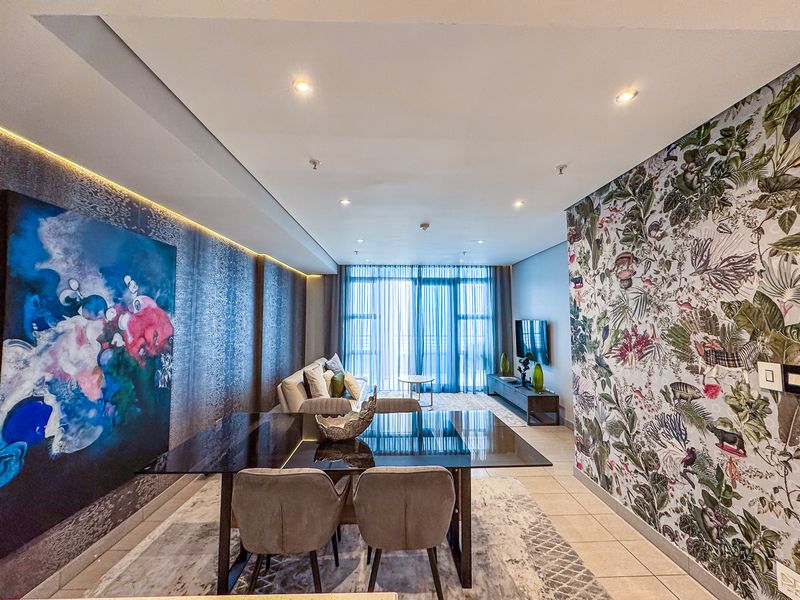 Modern open-plan living and dining area featuring recessed downlighting, cove lighting, tiled floors, and large sliding glass doors leading to a balcony.