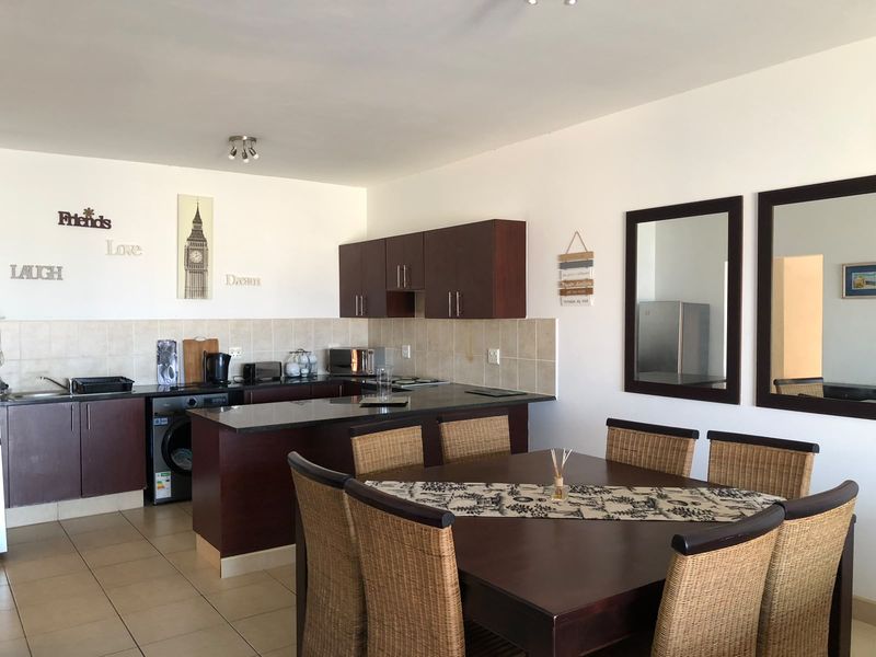 Open plan kitchen and dining area featuring dark wood cabinetry, granite countertops, tiled backsplash, and ceramic flooring.