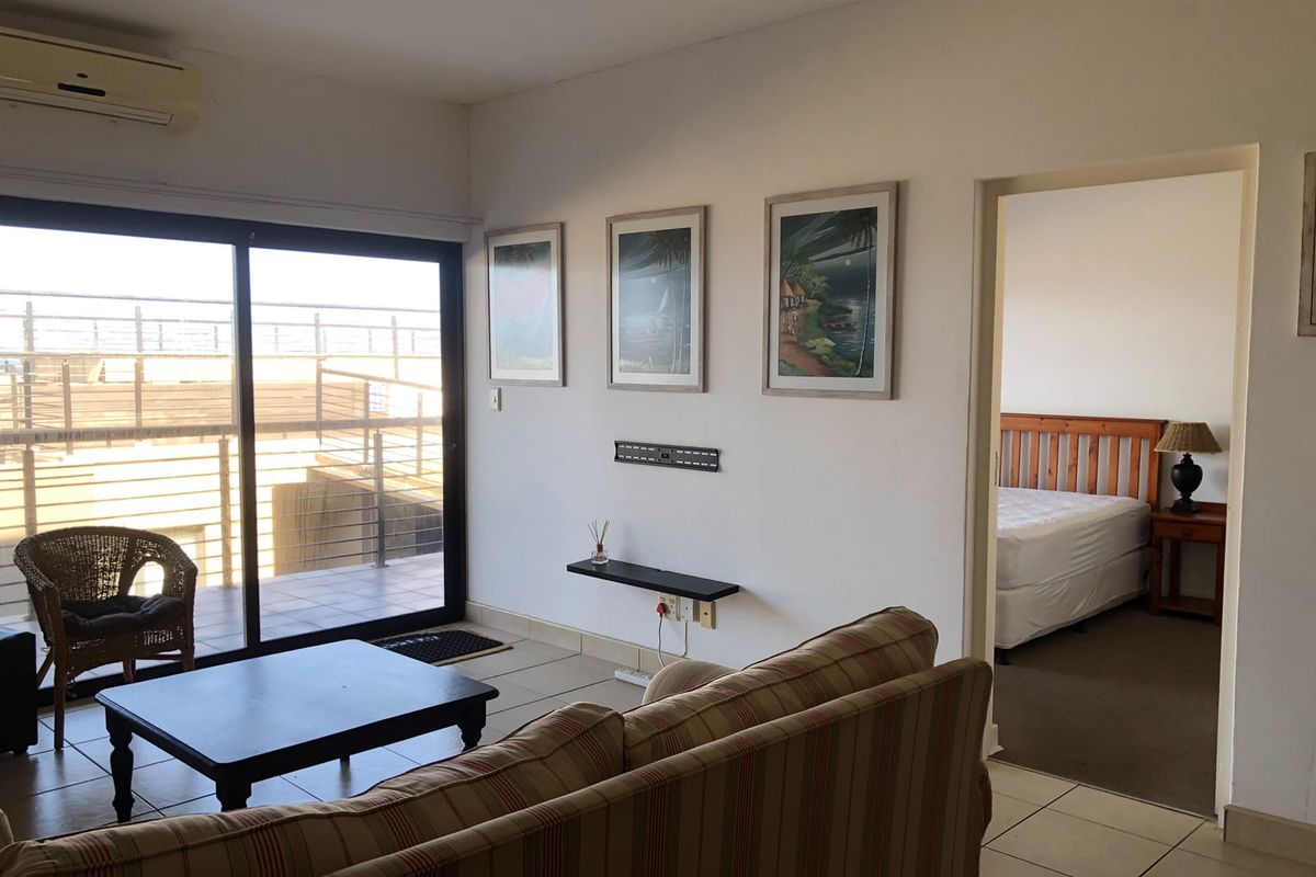 Living room featuring tiled flooring, a wall-mounted air conditioning unit, and sliding glass doors leading to an outdoor balcony area.