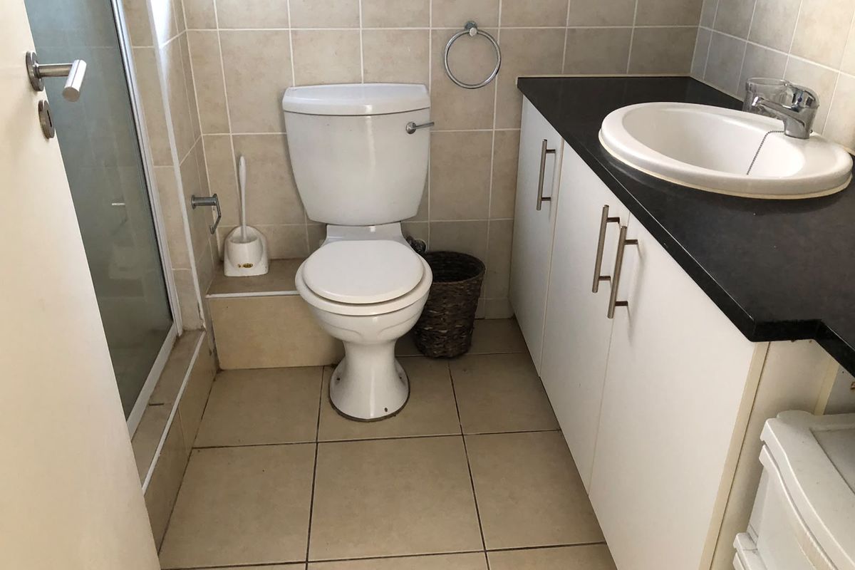 A functional bathroom featuring a vanity with a basin, a toilet, and a separate shower enclosure with tiled finishes throughout.