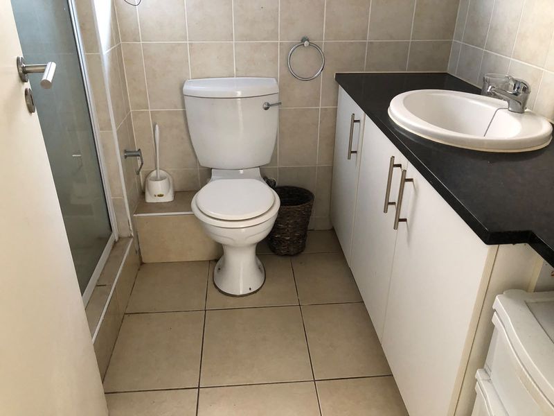 A functional bathroom featuring a vanity with a basin, a toilet, and a separate shower enclosure with tiled finishes throughout.