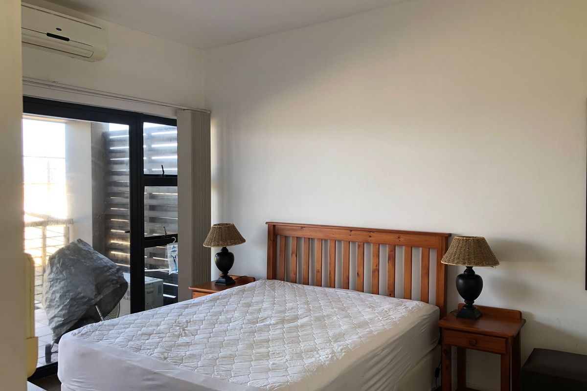 A bedroom featuring a split-system air conditioner and a sliding glass door providing access to an outdoor area.