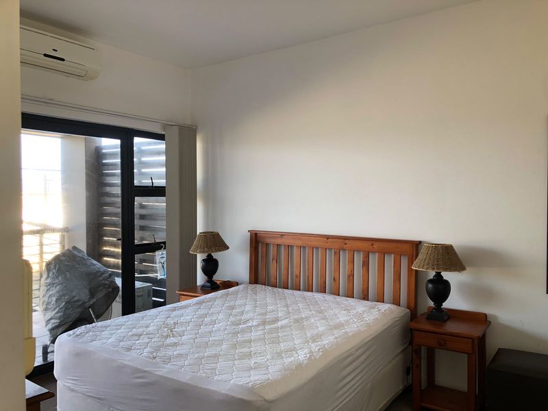 A bedroom featuring a split-system air conditioner and a sliding glass door providing access to an outdoor area.