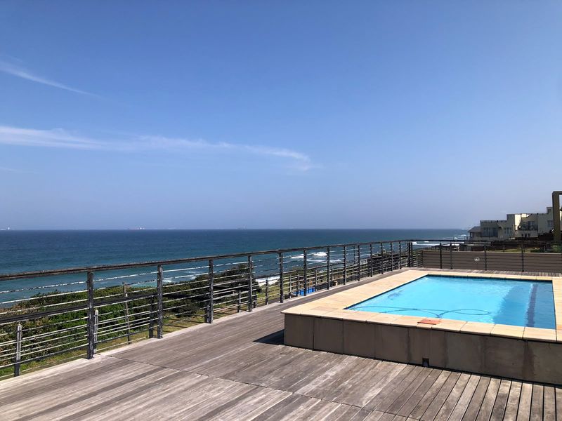 Elevated pool deck featuring timber flooring, a built-in swimming pool, and metal balustrades with expansive ocean views.