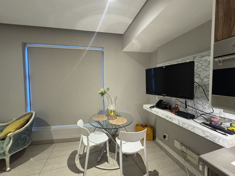 Open-plan living area featuring tiled flooring, a built-in marble-effect media wall with floating shelf, and recessed ceiling lighting.