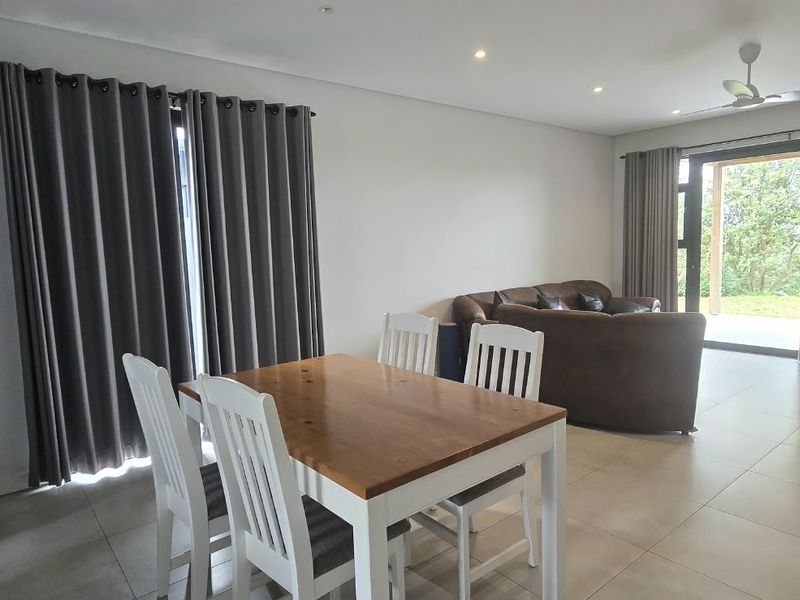 Spacious open-plan living and dining area featuring neutral tiled flooring, recessed lighting, and large sliding glass doors providing access to the outdoor space.