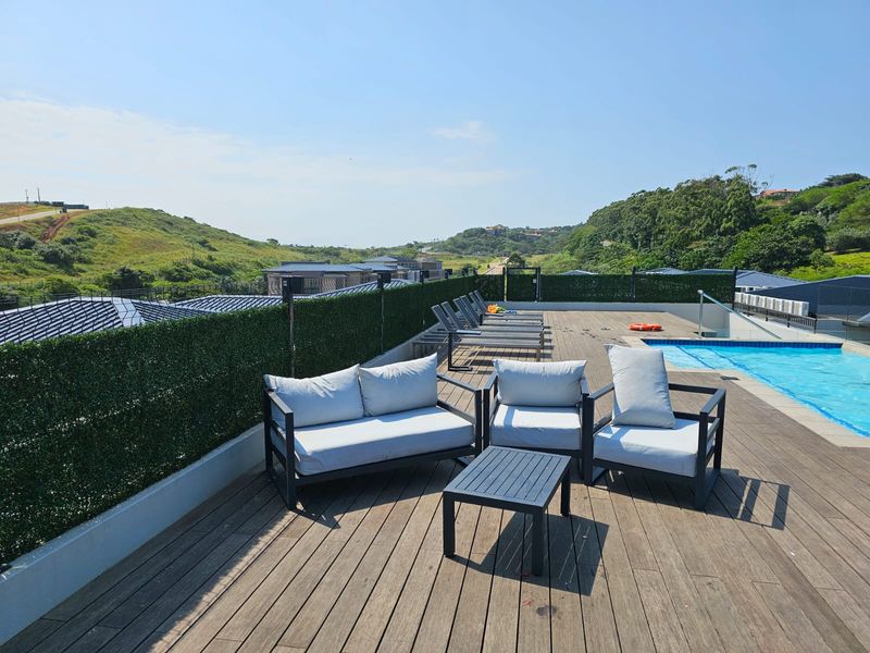 A well-maintained outdoor pool area featuring timber decking, privacy screening, and a clear view of the surrounding landscape.