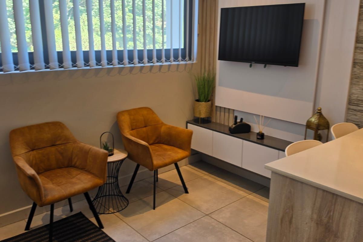 Modern living area featuring tiled flooring, a sleek built-in media console, feature wall paneling, and large windows with vertical blinds.