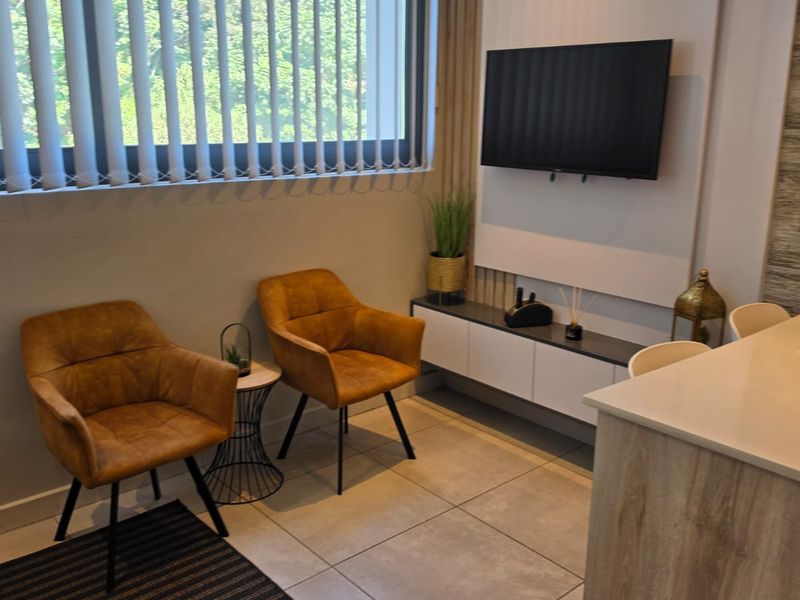 Modern living area featuring tiled flooring, a sleek built-in media console, feature wall paneling, and large windows with vertical blinds.