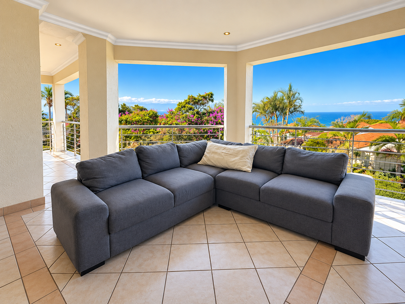 Spacious covered balcony featuring tiled flooring, stainless steel railings, and panoramic ocean views, providing an ideal outdoor living space.