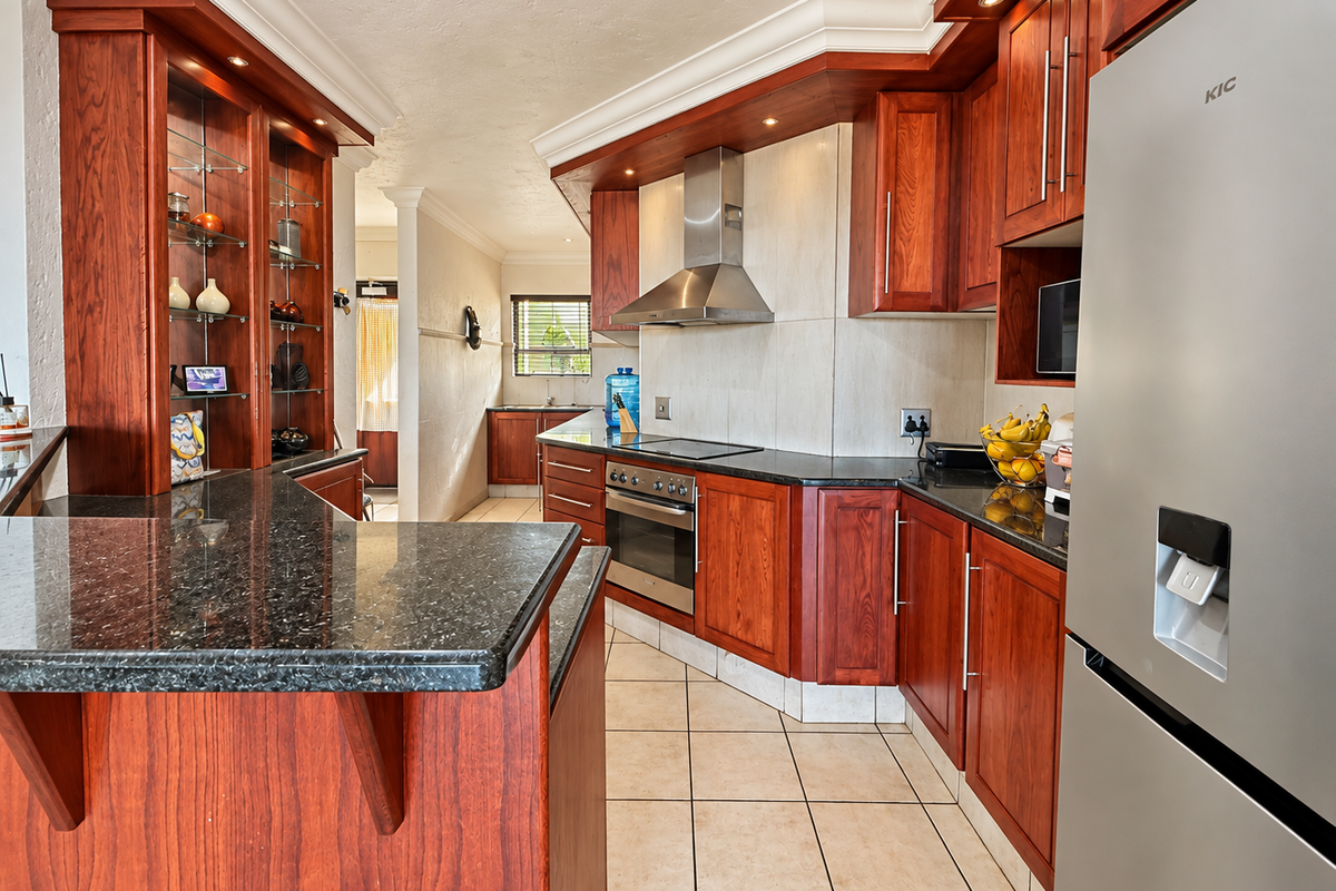 A well-maintained kitchen featuring rich wooden cabinetry, granite countertops, built-in stainless steel appliances, and integrated glass display shelving.