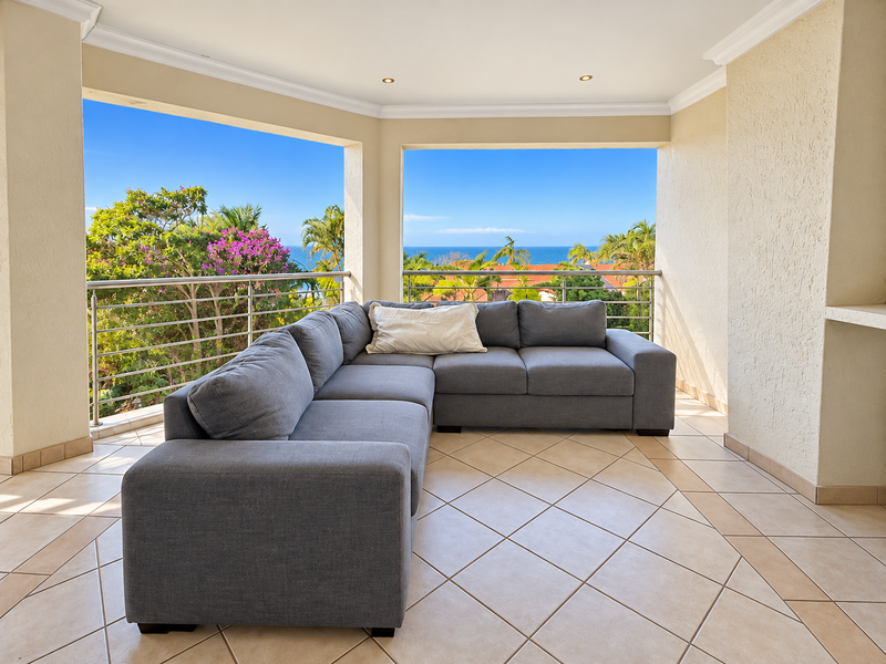 Spacious covered balcony featuring tiled flooring, stainless steel balustrades, and panoramic ocean views, providing an ideal outdoor living and relaxation space.