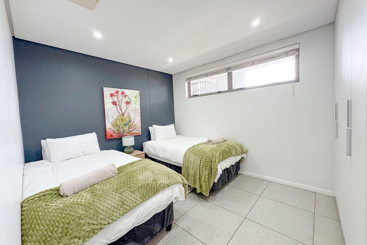 A well-maintained bedroom featuring tiled flooring, recessed downlighting, and built-in cupboards with a modern dark accent wall.