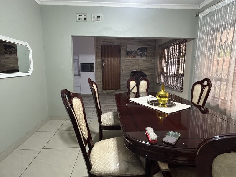 Dining room featuring tiled flooring, a stone feature wall, and access to an adjacent kitchen area.