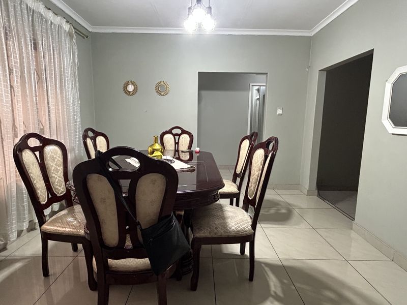 A dining room featuring tiled flooring, neutral wall paint, and a ceiling light fixture, providing a functional space for family meals.