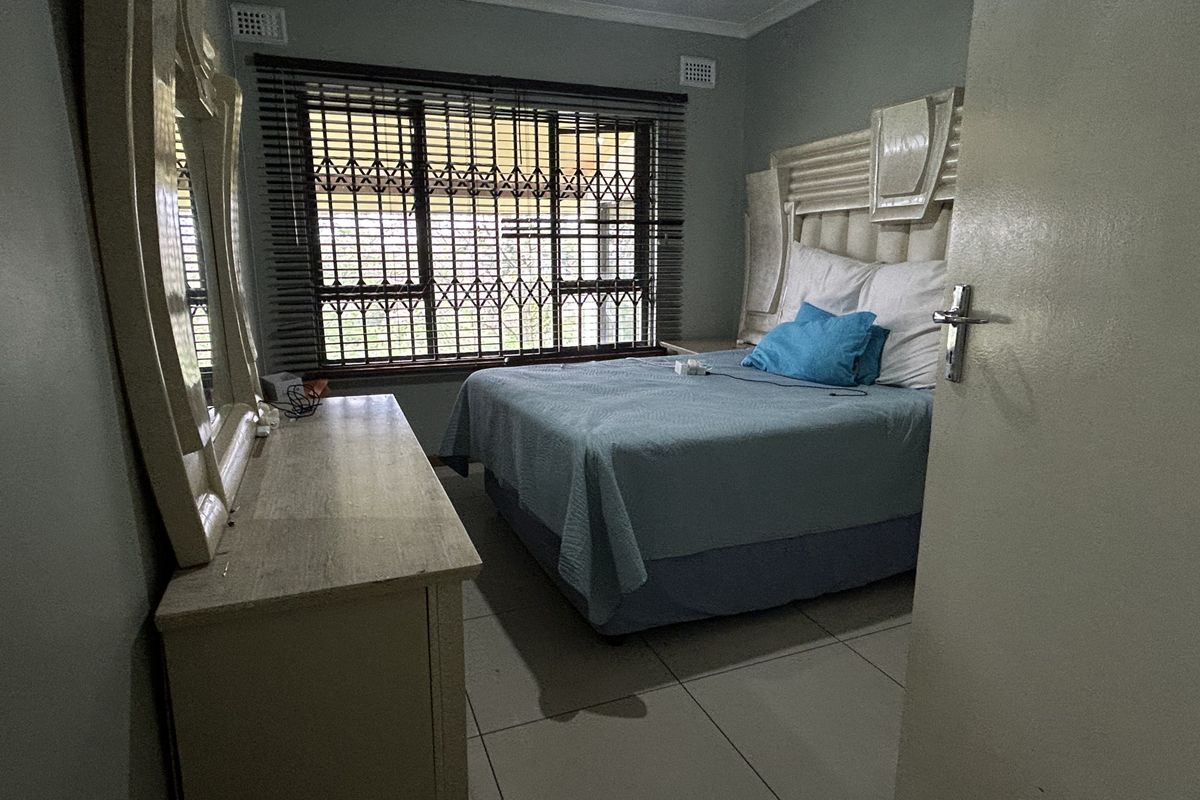 A functional bedroom featuring tiled flooring, security bars on the windows, and a built-in headboard, offering a neutral base for personalization.