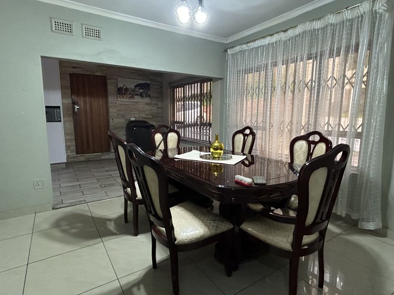 A dining room featuring tiled flooring, coving, and a large sliding door with a security gate leading to the exterior.