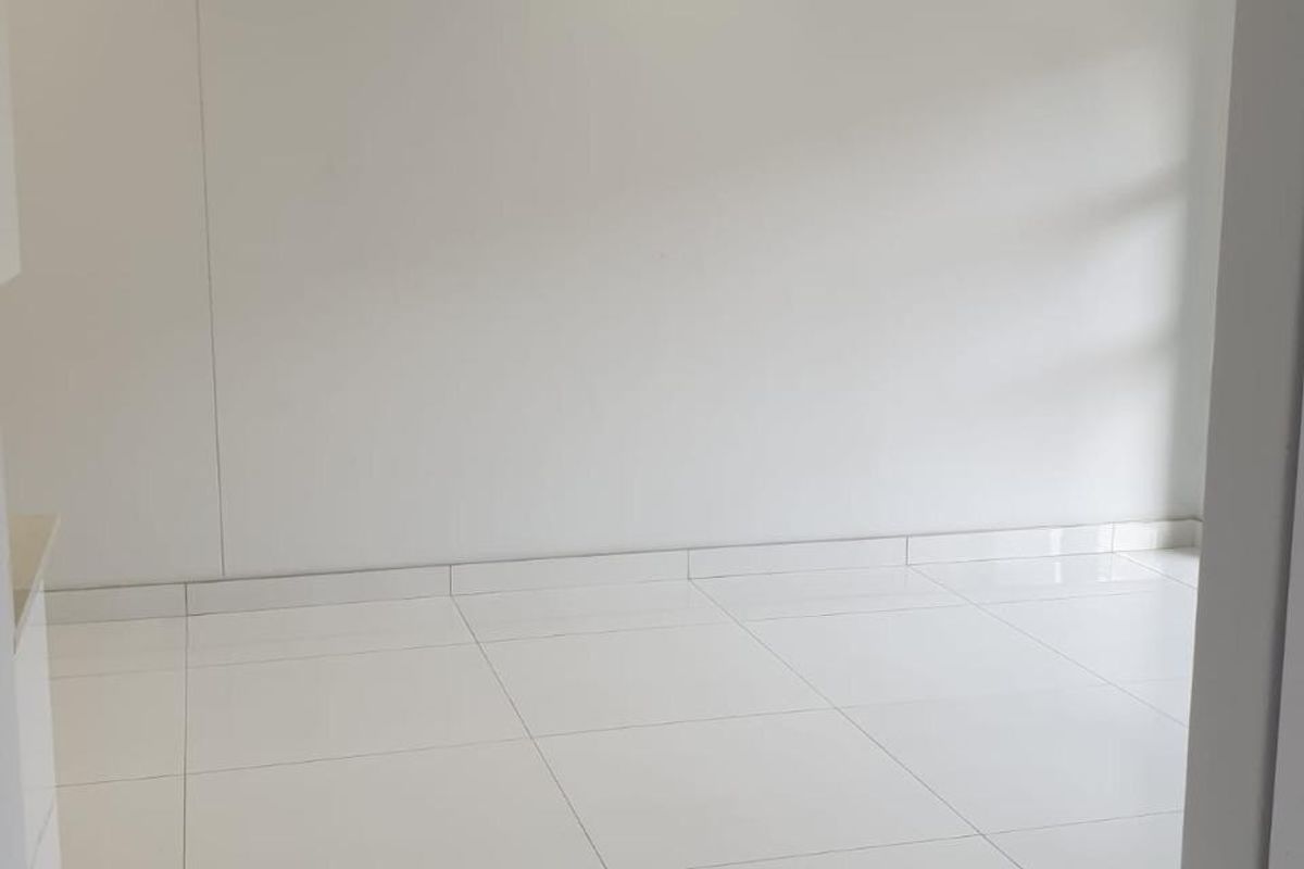 A bright, vacant living area featuring modern white porcelain floor tiles and recessed downlighting, offering a clean and neutral canvas for interior design.