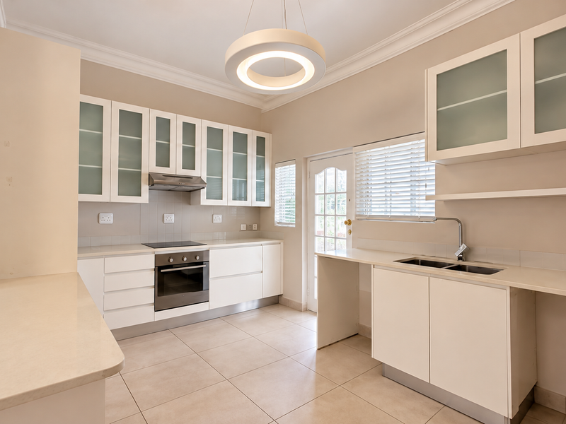 Modern kitchen featuring white cabinetry, built-in oven, electric hob, extractor fan, double sink, and tiled flooring with direct access to the exterior.