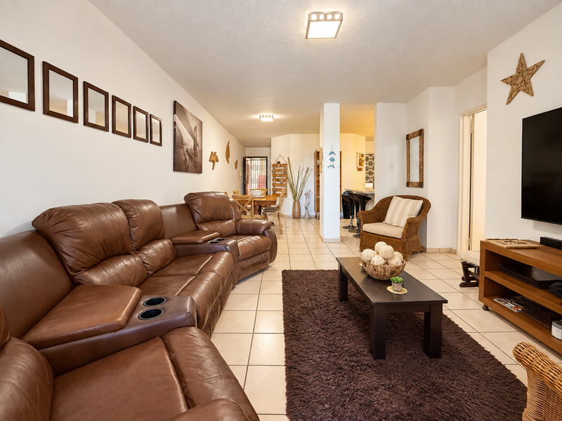 Spacious open-plan living and dining area featuring neutral ceramic floor tiles and a functional breakfast bar layout.