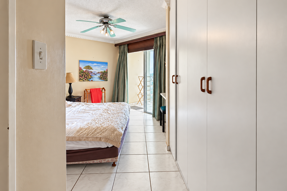 Bedroom featuring tiled flooring, built-in cupboards, a ceiling fan, and direct access to a private balcony through sliding glass doors.