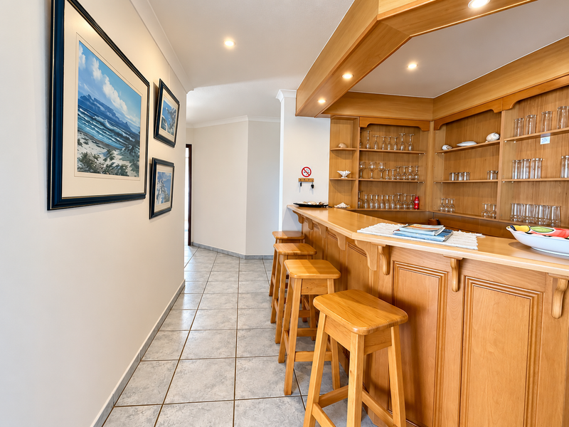 A well-maintained built-in wooden bar area featuring custom cabinetry, integrated shelving, and tiled flooring, providing a dedicated space for entertaining.