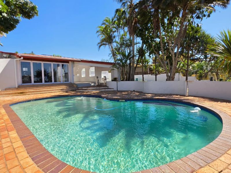 Outdoor pool area featuring a swimming pool with brick paving, a retaining wall, and access to a covered patio.