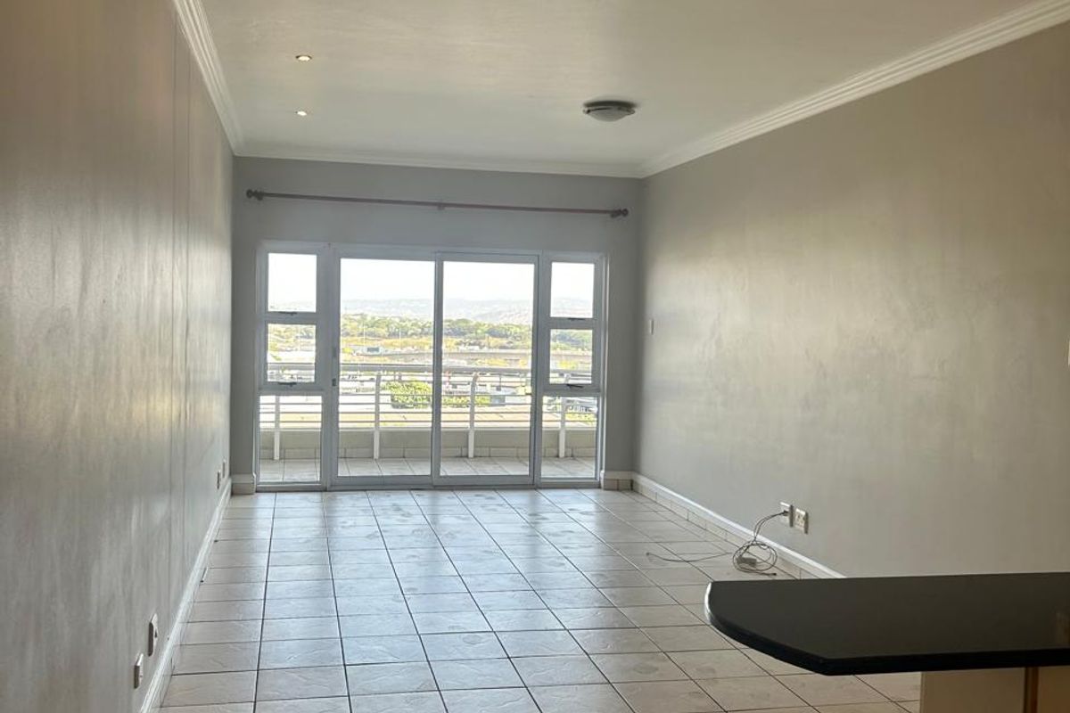Spacious open-plan living area featuring tiled floors, recessed lighting, and sliding glass doors leading to a balcony with scenic views.