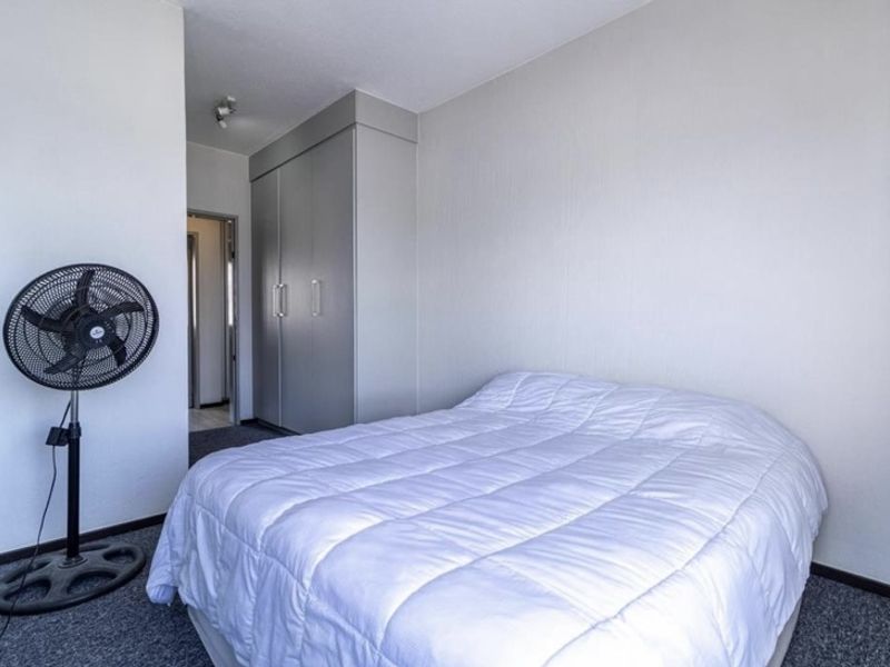 A functional bedroom featuring neutral walls, carpeted flooring, and a built-in wardrobe for storage.