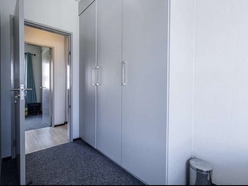 A clean hallway featuring built-in cupboards and access to an adjacent room.