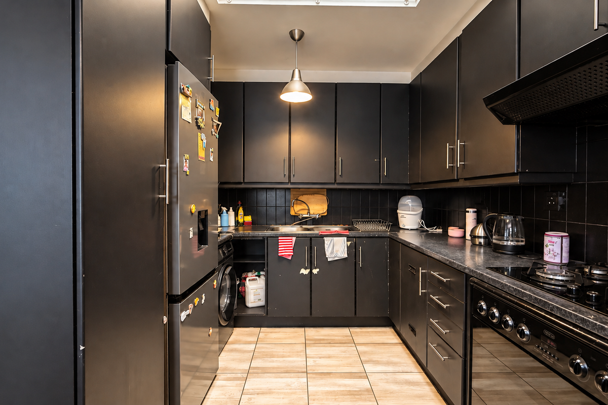 A modern kitchen featuring matte black cabinetry, a gas hob with extractor fan, built-in oven, and tiled backsplash with neutral floor tiles.