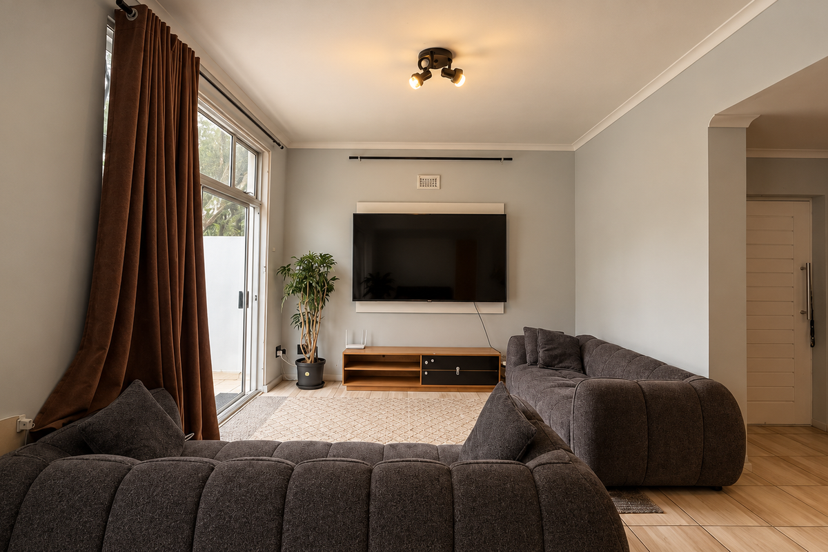 A well-maintained living room featuring tiled flooring, a sliding glass door providing natural light, and a modern ceiling light fixture.