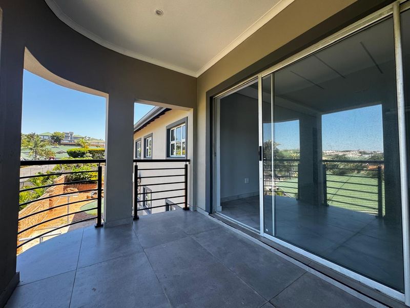 A covered balcony featuring tiled flooring, metal balustrades, and large sliding glass doors providing access to the interior living space.