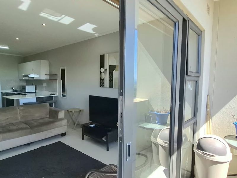 Open-plan living area featuring a modern kitchen and seamless access to a private balcony through large sliding glass doors.