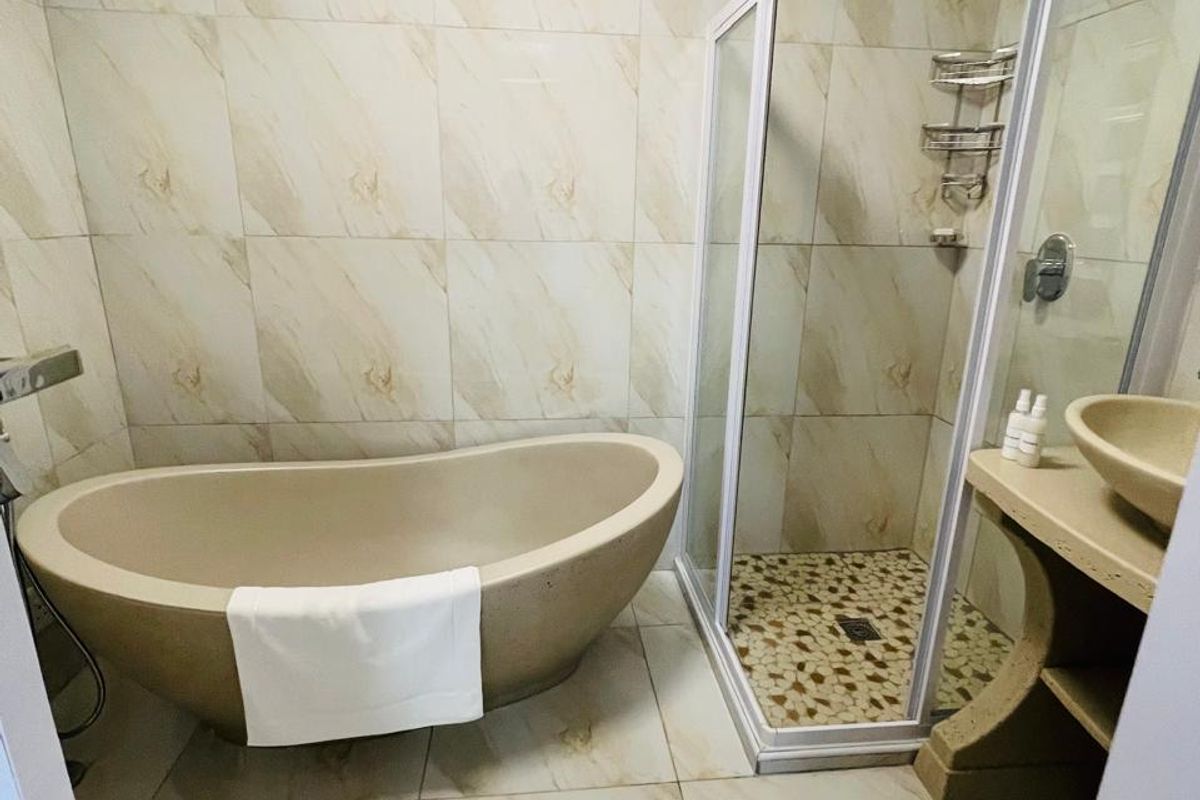 Modern bathroom featuring a freestanding bathtub, a separate glass-enclosed shower, and a stone vanity with a vessel sink.