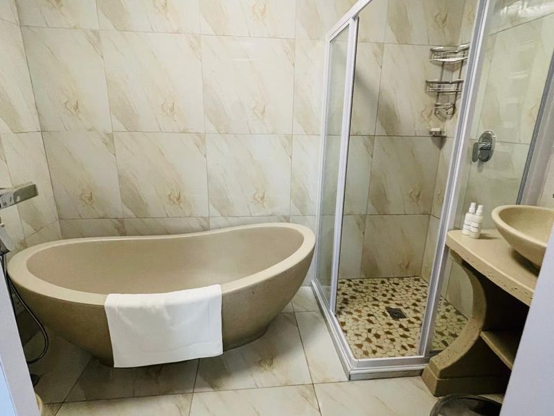 Modern bathroom featuring a freestanding bathtub, a separate glass-enclosed shower, and a stone vanity with a vessel sink.