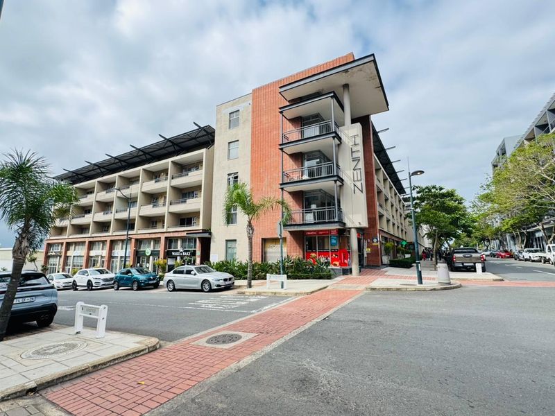 Exterior view of the Zenith apartment building featuring a modern brick facade, multiple balconies, and ground-level commercial storefronts.