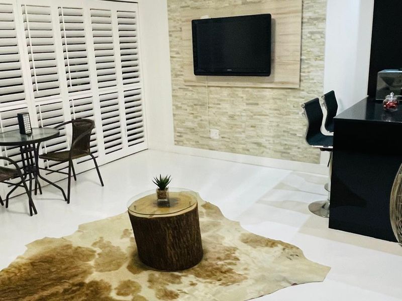 Open plan living area featuring a stone accent wall, plantation shutters, and a sleek built-in breakfast bar.