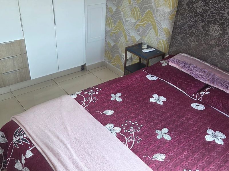 A bedroom featuring tiled flooring and a built-in wardrobe with a combination of white and wood-grain finishes.