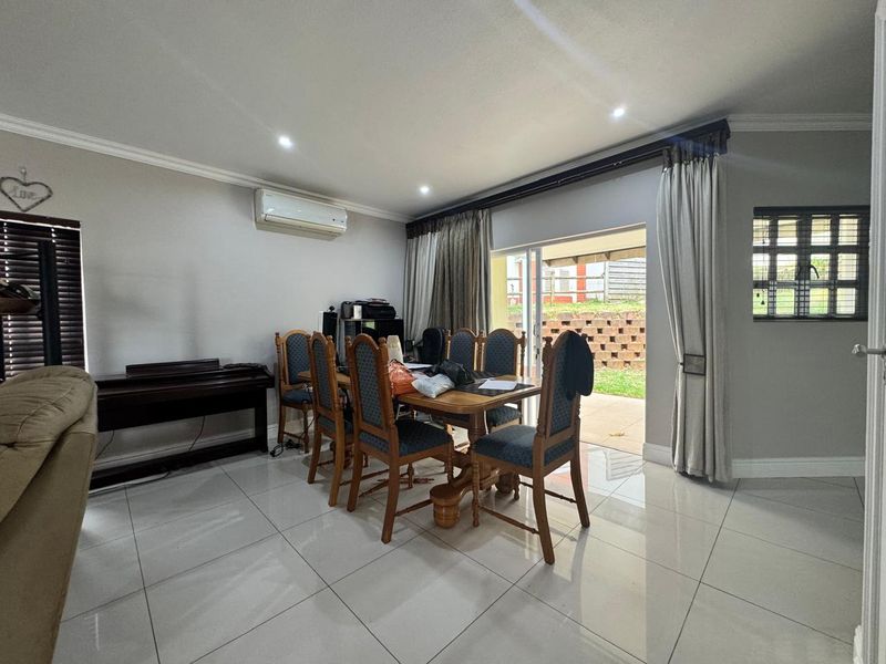 Dining area featuring polished porcelain floor tiles, recessed lighting, split-system air conditioning, and direct access to the rear patio through a sliding glass door.
