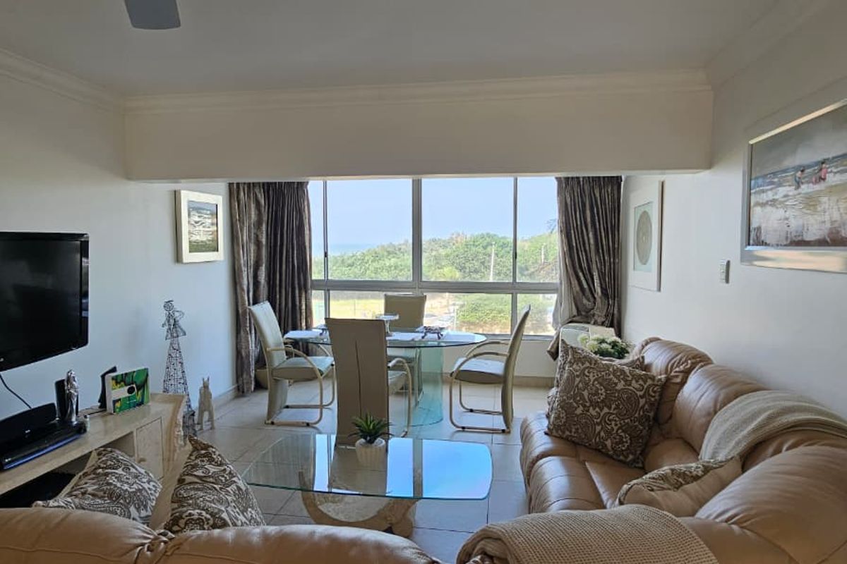 Open-plan living and dining area featuring large windows with natural light, tiled flooring, and a ceiling fan, offering a comfortable and functional living space.