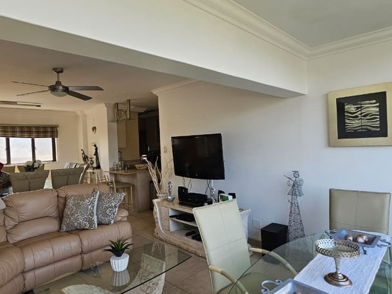 An open-plan living and dining area featuring tiled flooring, coved cornicing, and a ceiling fan, seamlessly connected to the kitchen space.